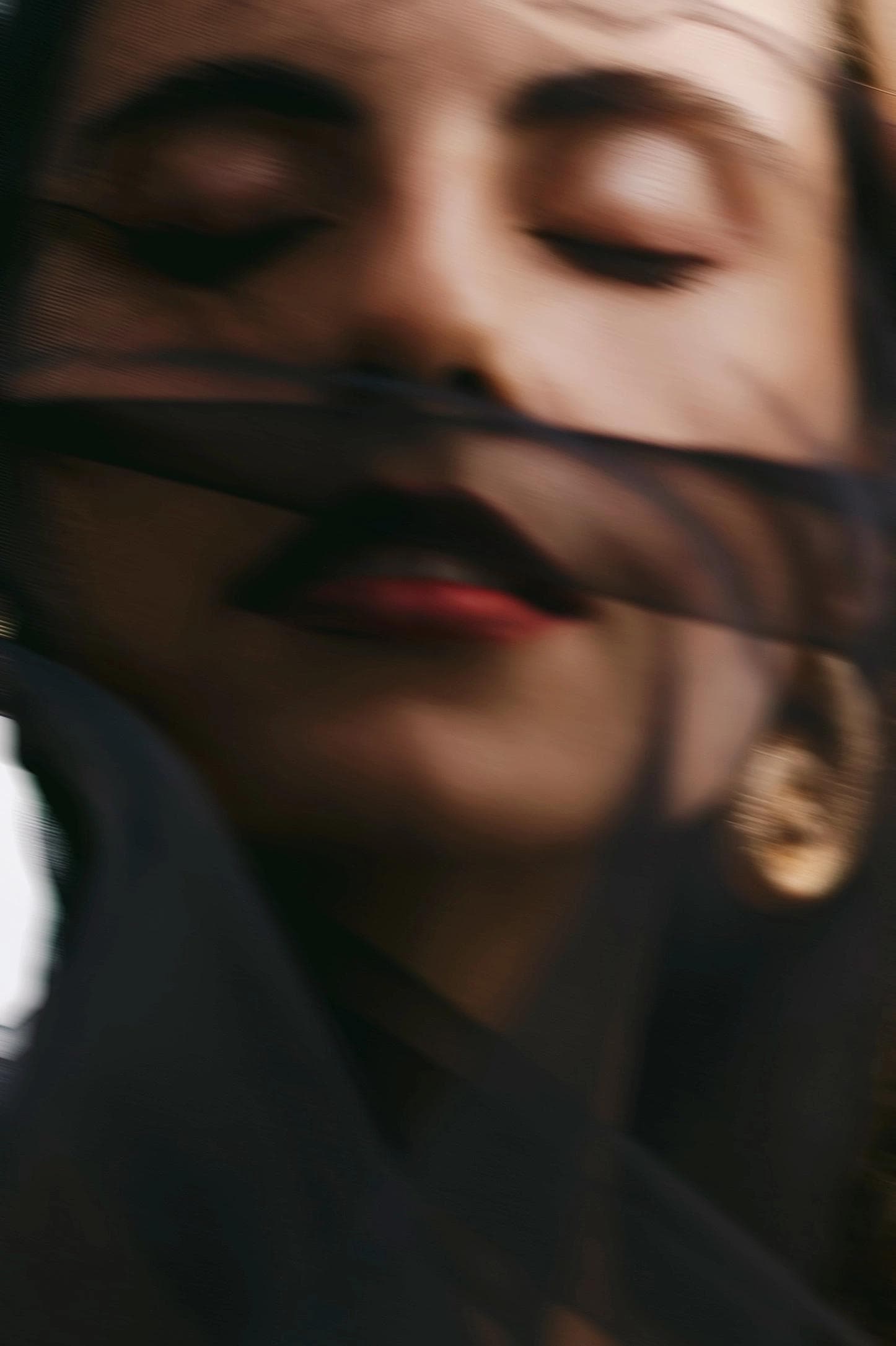 detail of model's face with black veil in front